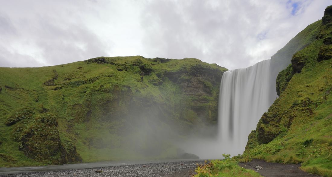 Skógafoss waterfall pouring over a green cliff in south Iceland