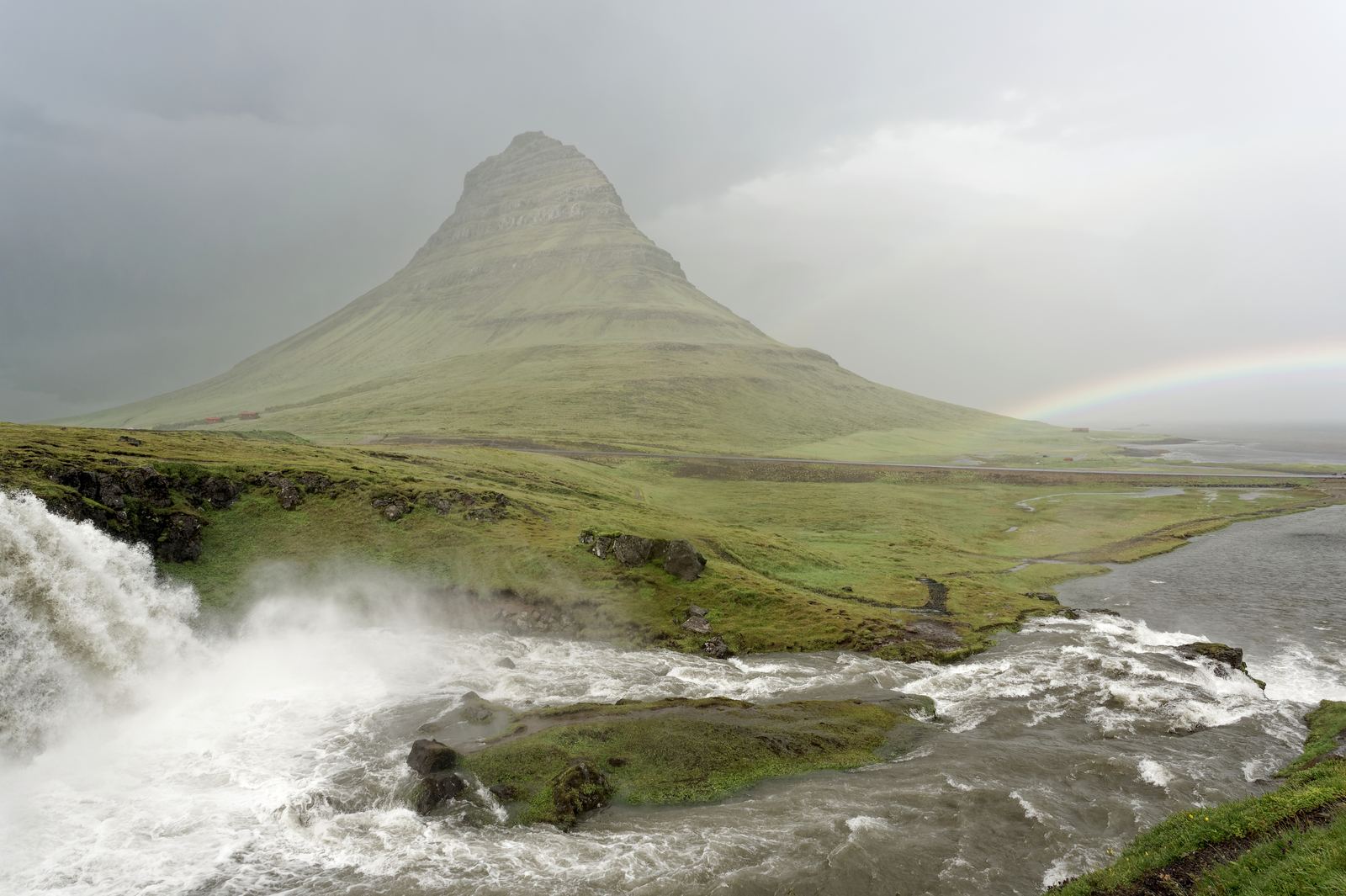 The cone-shaped Kirkjufell mountain rising above a green coastal plain in west Iceland